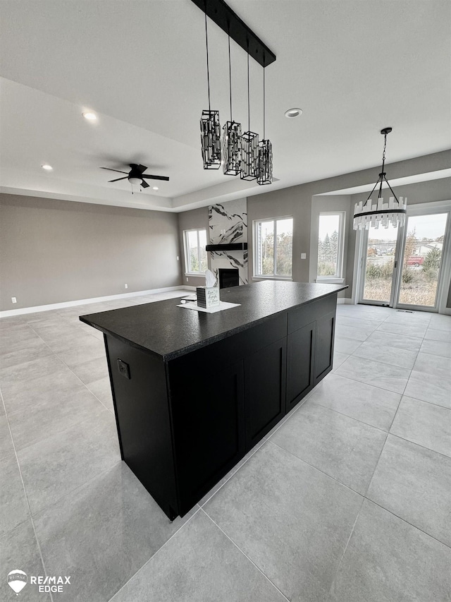 kitchen featuring a high end fireplace, dark countertops, a kitchen island, open floor plan, and dark cabinets