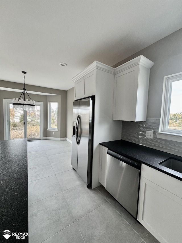 kitchen with dark countertops, tasteful backsplash, appliances with stainless steel finishes, white cabinetry, and a sink