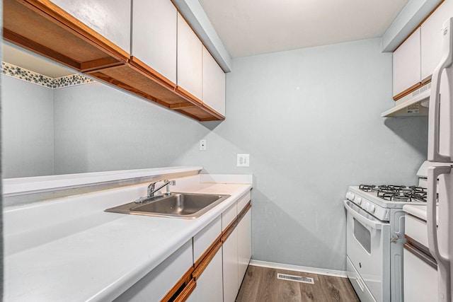 kitchen with a sink, white appliances, white cabinetry, and light countertops