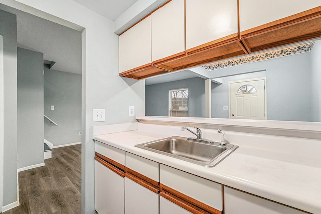 kitchen with baseboards, dark wood finished floors, light countertops, white cabinetry, and a sink