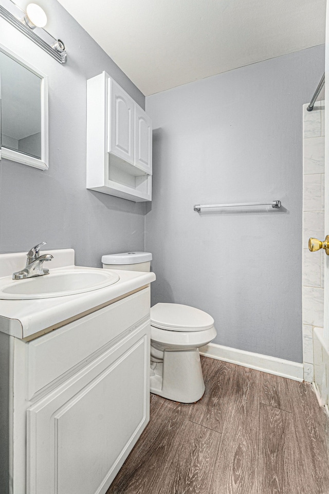 bathroom featuring vanity, toilet, wood finished floors, and baseboards