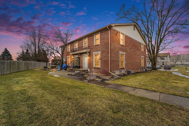 exterior space with a yard, fence, and brick siding