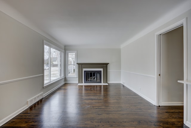 unfurnished living room featuring a fireplace with flush hearth, baseboards, visible vents, and dark wood-style flooring