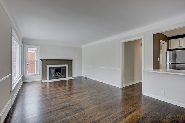 unfurnished living room featuring baseboards, a fireplace with flush hearth, and dark wood finished floors