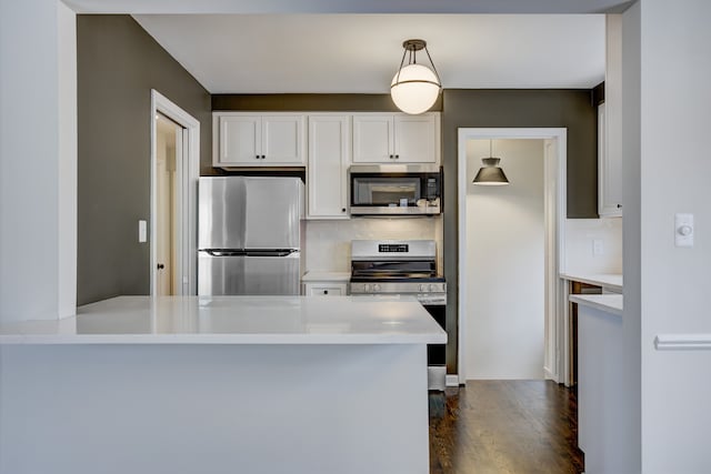 kitchen with tasteful backsplash, dark wood finished floors, stainless steel appliances, white cabinets, and light countertops