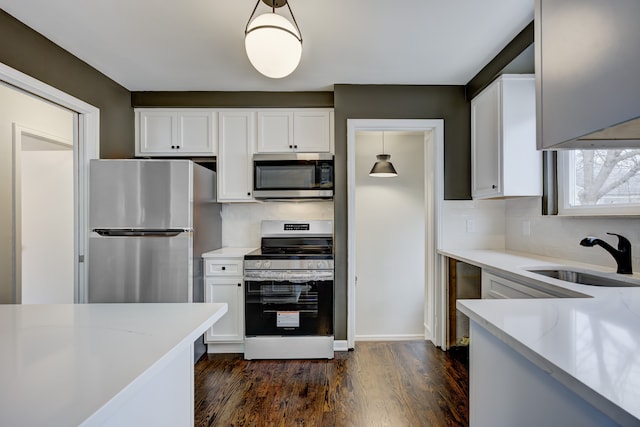 kitchen featuring a sink, tasteful backsplash, appliances with stainless steel finishes, white cabinets, and dark wood-style flooring