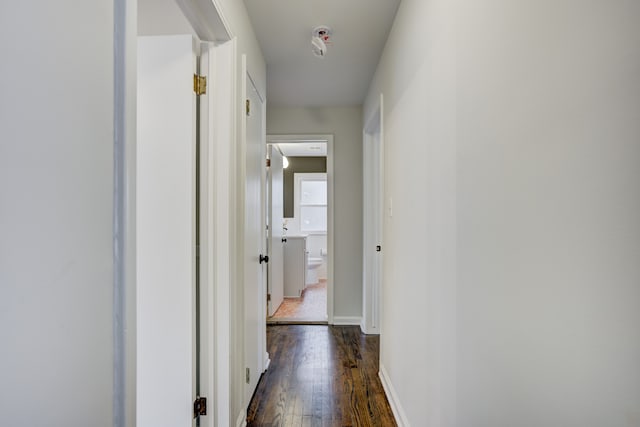 corridor with dark wood-type flooring and baseboards