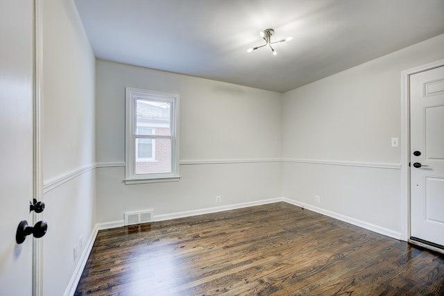 spare room featuring visible vents, baseboards, and dark wood-style flooring