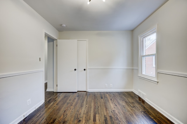 spare room featuring visible vents, baseboards, and dark wood-style flooring