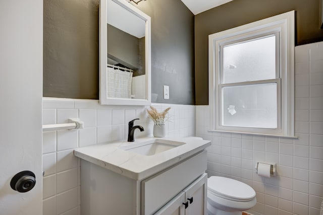 full bath featuring vanity, tile walls, and toilet