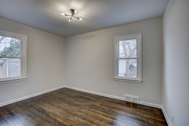 empty room with visible vents, baseboards, and dark wood-style flooring