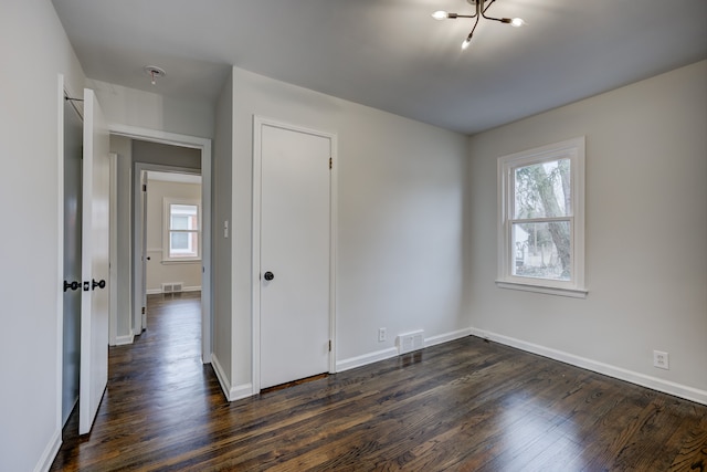 unfurnished room with visible vents, dark wood-type flooring, and baseboards