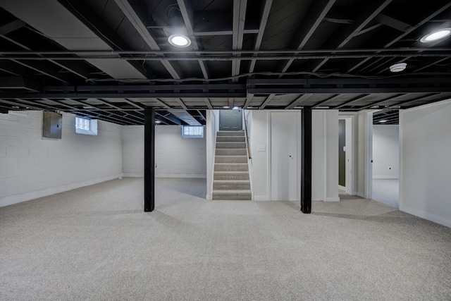 below grade area featuring electric panel, carpet floors, a healthy amount of sunlight, and stairs