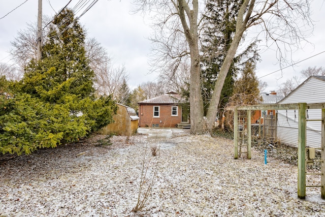 rear view of property with crawl space, brick siding, an outdoor structure, and fence