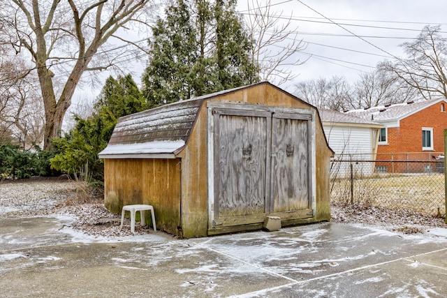 snow covered structure featuring a storage shed, fence, and an outdoor structure