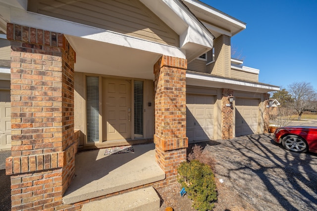 property entrance featuring aphalt driveway and brick siding