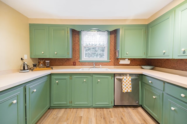 kitchen with stainless steel dishwasher, light countertops, light wood-style flooring, and a sink