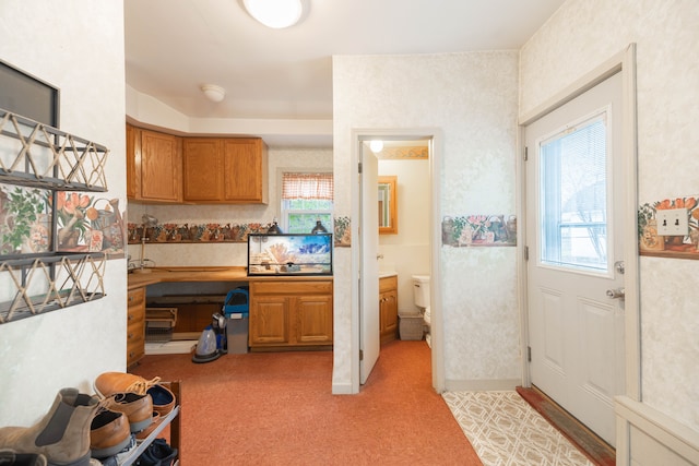 kitchen featuring brown cabinetry and light carpet