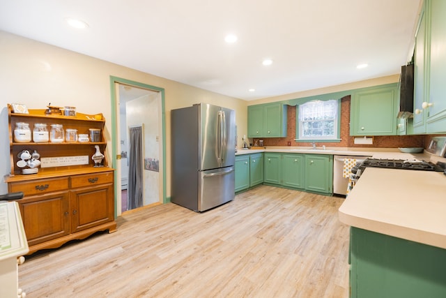 kitchen with green cabinetry, light countertops, appliances with stainless steel finishes, light wood-style floors, and a sink