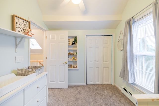 interior space with baseboards, ceiling fan, light colored carpet, vaulted ceiling with skylight, and a closet