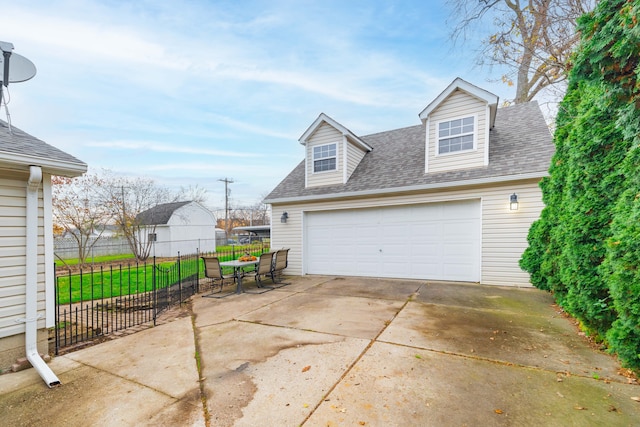 exterior space featuring a shingled roof, a garage, and fence