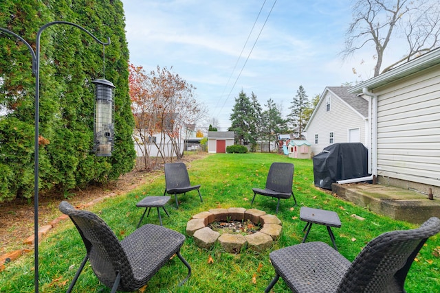 view of yard featuring a storage shed, fence, an outdoor structure, and an outdoor fire pit