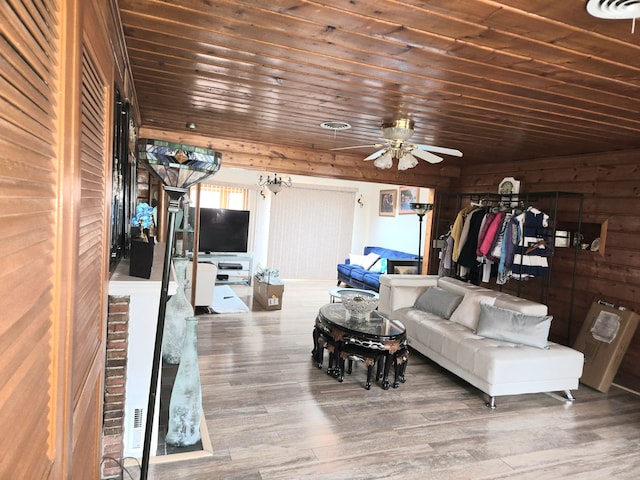 living area with wood finished floors, visible vents, ceiling fan, wood walls, and wooden ceiling