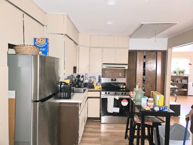 kitchen with extractor fan, white cabinets, light wood-style floors, and stainless steel appliances