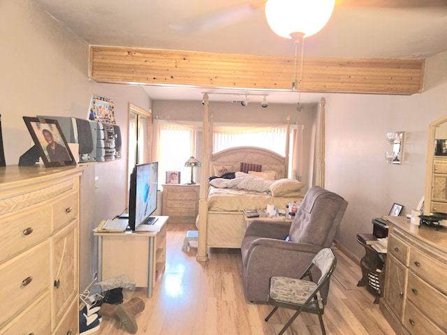 bedroom featuring beam ceiling and light wood-style flooring