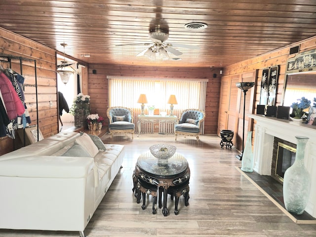 living room with visible vents, wood walls, a fireplace, and wood finished floors