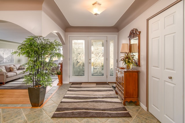 foyer with french doors, arched walkways, and baseboards