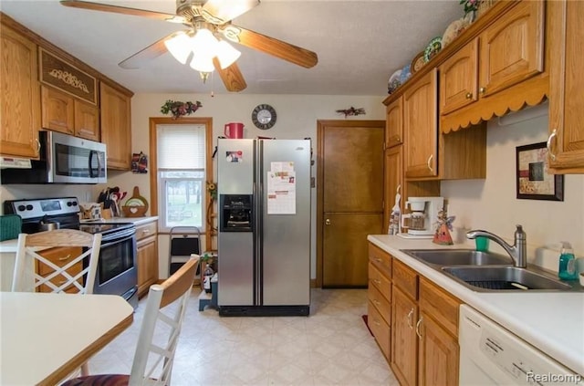 kitchen featuring brown cabinets, a sink, appliances with stainless steel finishes, light countertops, and light floors