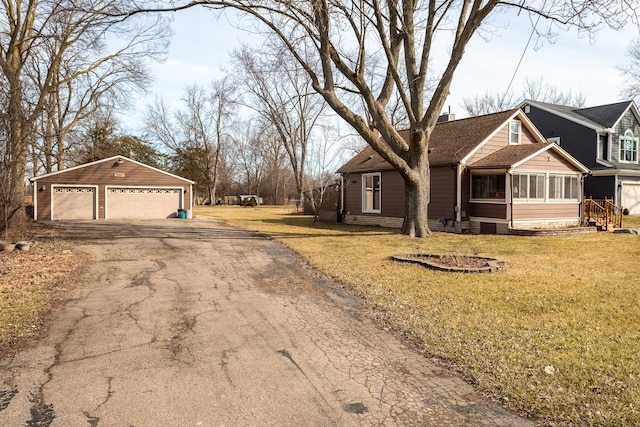 view of front of home featuring an outbuilding, a front lawn, a garage, and a sunroom