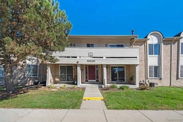 view of property with a balcony and a front lawn