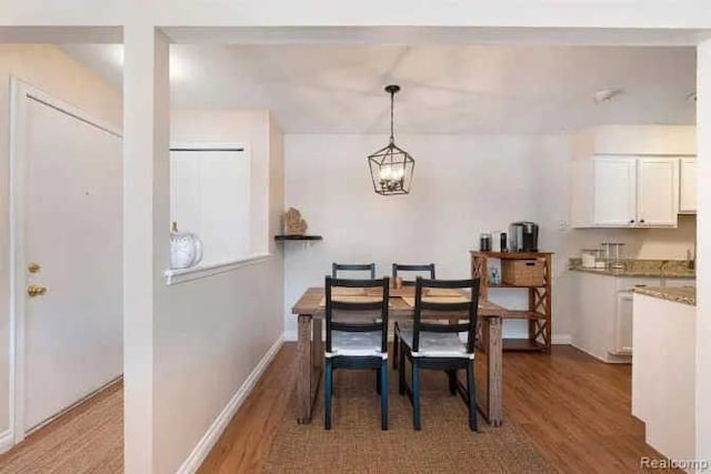 dining area with wood finished floors, baseboards, and a chandelier