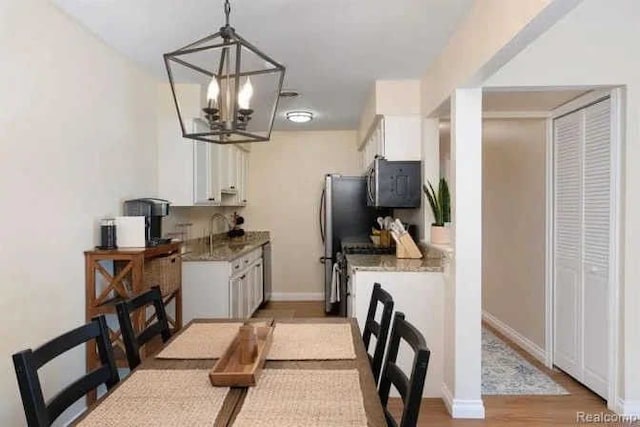 dining room featuring light wood-style flooring, baseboards, and an inviting chandelier