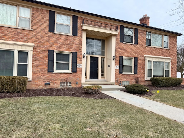 view of front of property featuring brick siding, crawl space, a chimney, and a front lawn