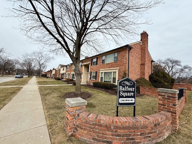 view of front of home featuring a front lawn, brick siding, and a chimney