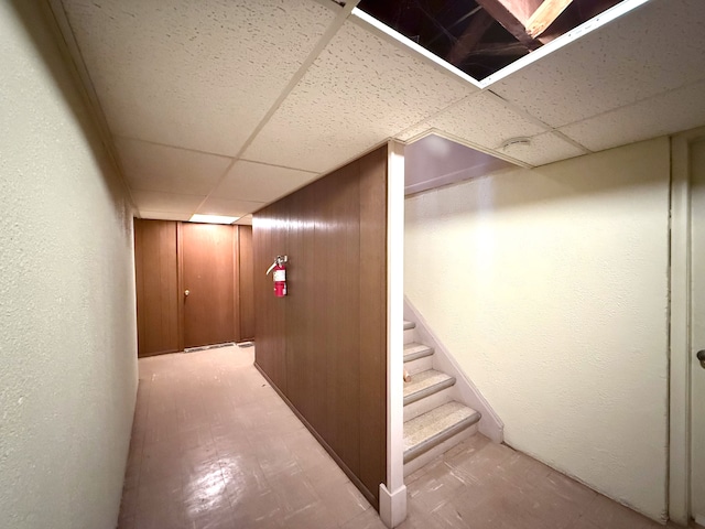 corridor featuring stairs, a paneled ceiling, and a textured wall