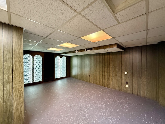 unfurnished room featuring a paneled ceiling and wooden walls