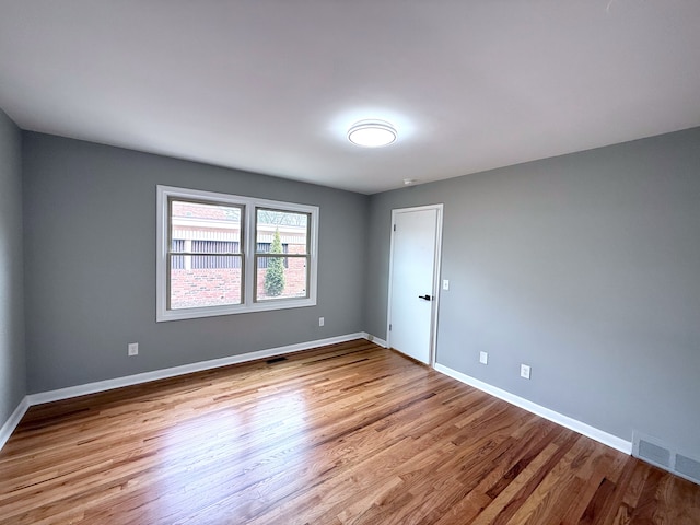 empty room with visible vents, baseboards, and wood finished floors