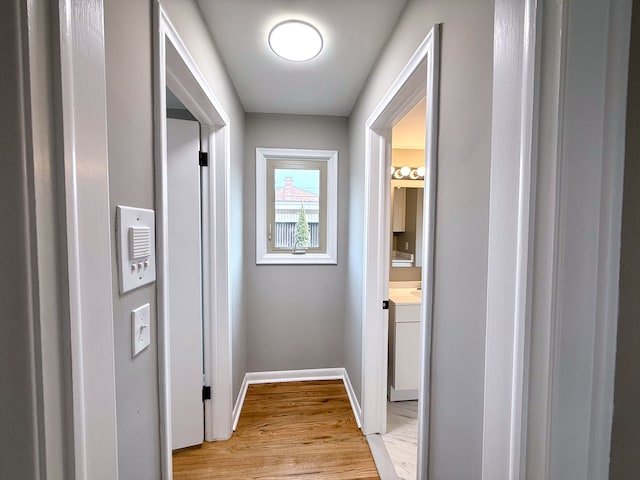 hallway featuring light wood finished floors and baseboards