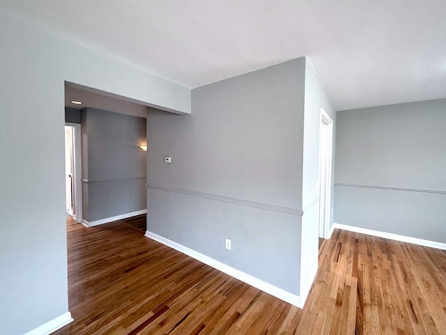 spare room featuring baseboards and wood finished floors