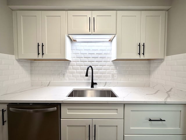 kitchen featuring dishwasher, decorative backsplash, light stone countertops, and a sink