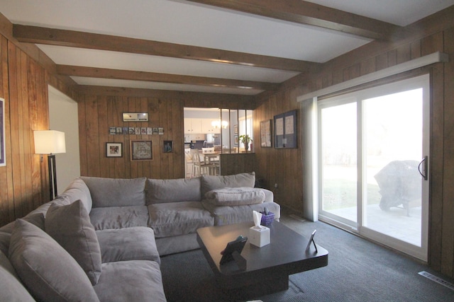 living area with visible vents, wooden walls, carpet, and beamed ceiling