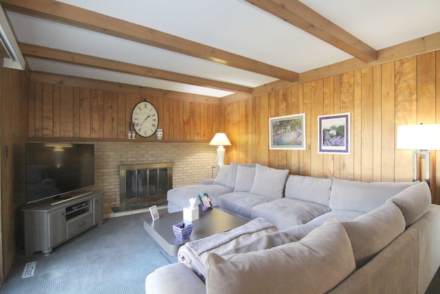 living room featuring beamed ceiling, light carpet, visible vents, wooden walls, and a brick fireplace