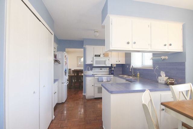 kitchen featuring white cabinets, white appliances, a peninsula, and a sink