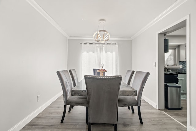 dining space with a chandelier, baseboards, wood finished floors, and crown molding