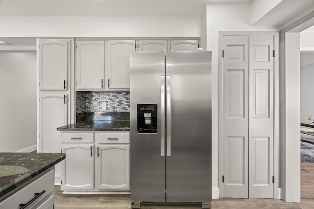 kitchen with decorative backsplash, dark stone countertops, light wood-type flooring, and stainless steel fridge with ice dispenser
