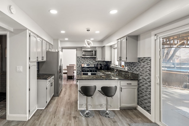 kitchen featuring a peninsula, backsplash, appliances with stainless steel finishes, and a sink